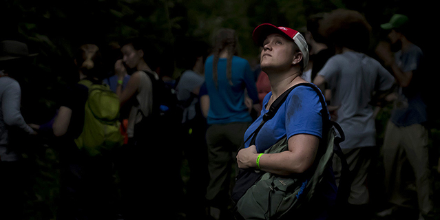 A woman in the foreground lit by the moon with students in the background (C) Curtis Creager  