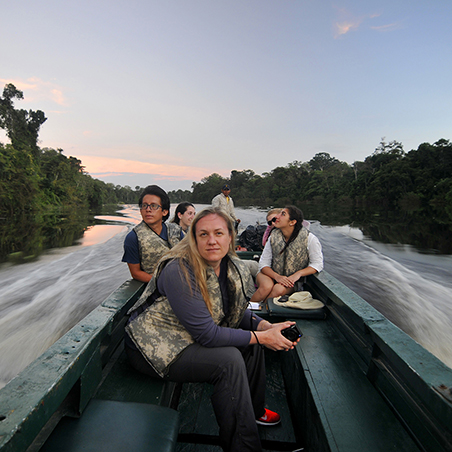 A woman sitting on a boat with students in the background in Peru. (C) Curtis Creager  